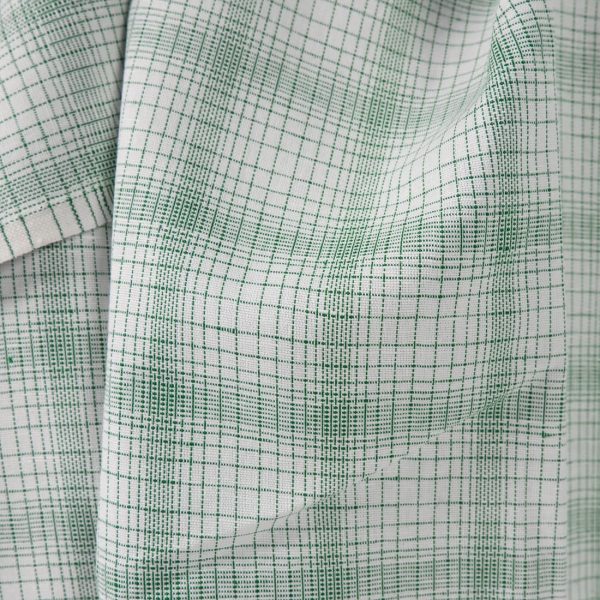 White linen cotton fabric with striped green checks close up view of pattern