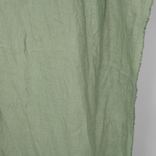 Washed linen fabric in muted light green, fabric edge